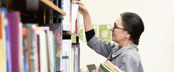 Person taking book from bookshelf